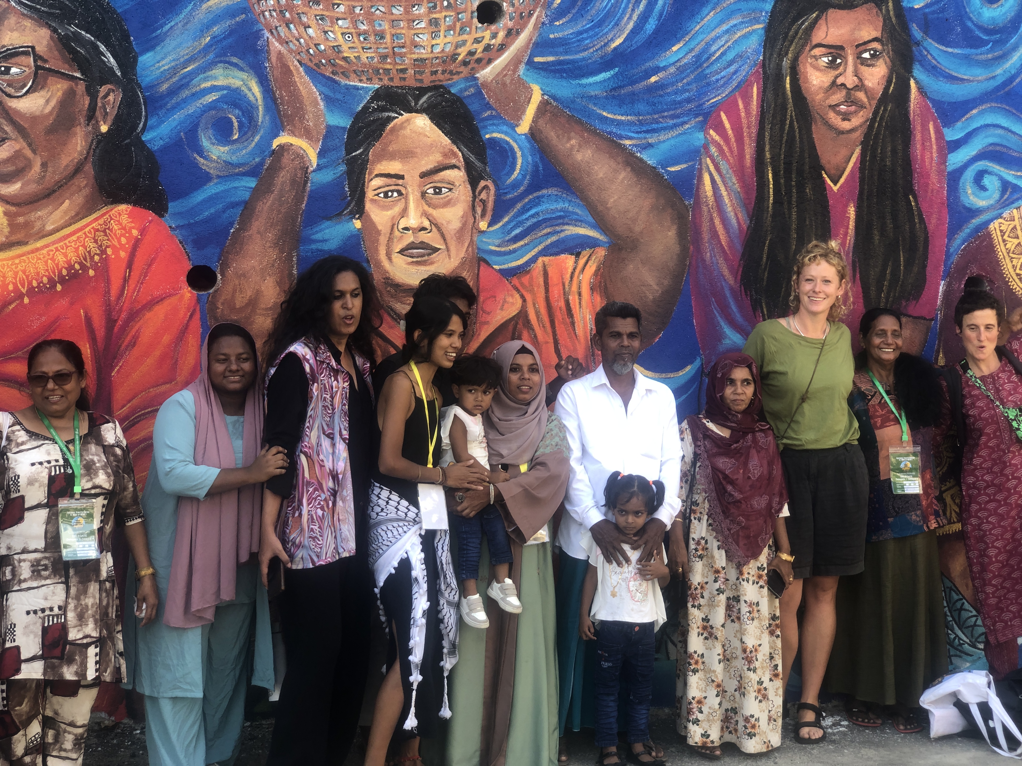 Nyeleni 2025 mural with delegates gathered in front of the artwork. - ACHFN, African & Caribbean Heritage Food Network